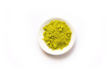 Japon kibrit çayının yeşil tozu, beyaz arka planda izole bir tabakta. Gevşek barut. Mesaj için yer var. Kafe ve yemek, canlandırıcı bir içeceğin bileşeni.
