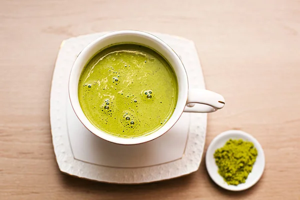 Japanese matcha green tea is poured into a white mug and on a white saucer in powder. Tea set on a textured napkin. Invigorating drink in a cafe, cooking, cheerfulness, antioxidant. space for text
