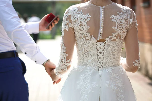 Back of the bride in a white wedding dress close-up. Bride fees, wedding ceremony, wedding salon, dress shop for the celebration. Decor, lace, buttons, custom tailoring