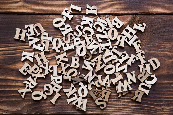 Letters of the English alphabet on a dark wooden background. The concept of education, word games, needlework. Space for text