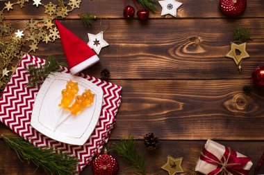 2021 yılının sembolü olan iki lolipop, beyaz çay tabağında boğa, süslemeli havlu ve ahşap arka planda Noel dekoru. Mücevher yıldızları, boncuklar, balo, köknar. Düz yat, boşluğu kopyala