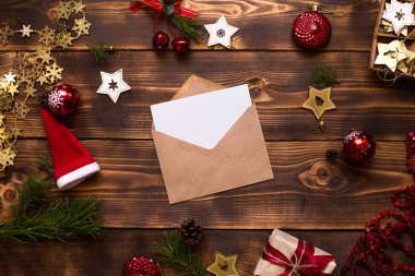 El işi kağıdından yapılmış bir zarf, beyaz bir çarşaf ve ahşap bir arka planda Noel dekoru olan bir yazı. Noel Baba 'ya bir mektup, bir dilek listesi, bir yılbaşı hayali, bir hediye. Düz yat, boşluğu kopyala
