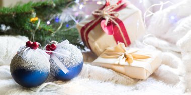 Yapay karlı mavi toplar, Noel hediyesi kutuları ve beyaz örülü battaniye üzerindeki süslemeler. Yeni yıl, şenlikli atmosfer, ladin dalı, konfor. Metin için boşluk