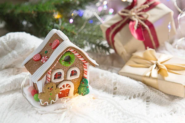 ガーランドやスプルースの枝の光の中で白いニットブランケットにクリスマスプレゼントや装飾ジンジャーブレッドハウスとボックス お祝いの雰囲気 テキストのスペース — ストック写真