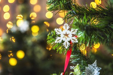 Yeşil Noel ağacı Noel oyuncaklar ve sarı ışık ile çelenk süslenmiş. Arka planda sarı bulanık ışık.