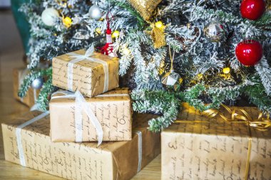 Hediyeler Noel oyuncaklar ve mumlarla süslenmiş yeşil Noel ağacının altında kırmızı ve beyaz ambalajın Paketli. Arka planda bir kurabiye evi ise sarı Noel ışıkları