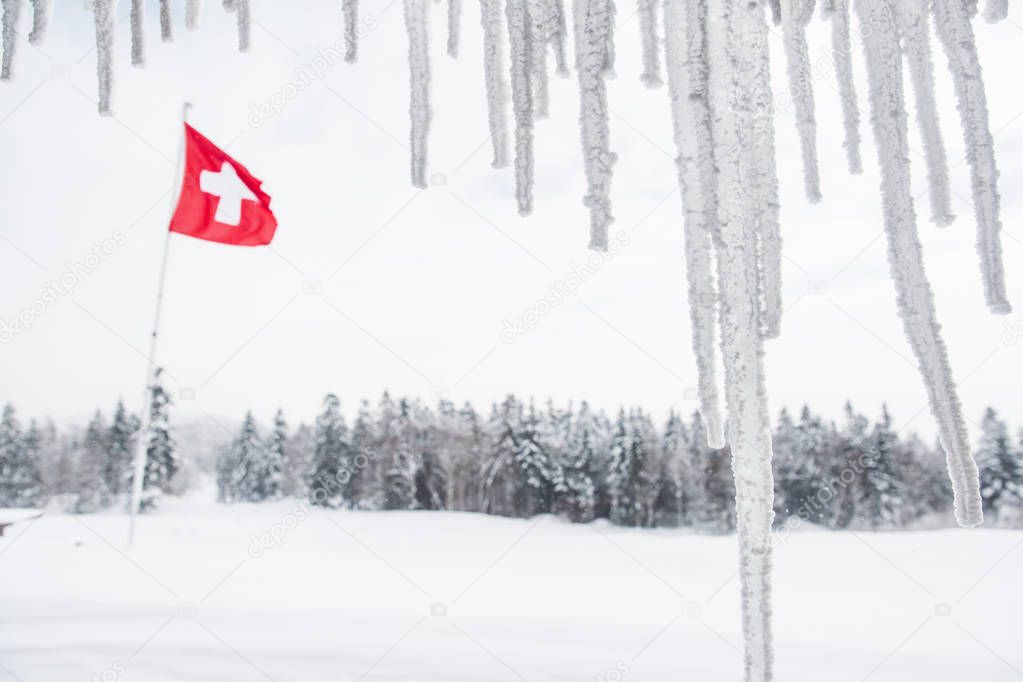 Swiss Flag Floating behind Chalet Stalactites in Winter