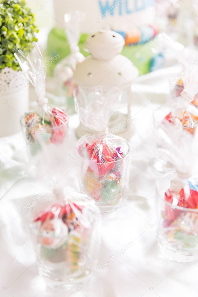 Glasses of Bagged Sweets on White Table with White Decorative Lamp