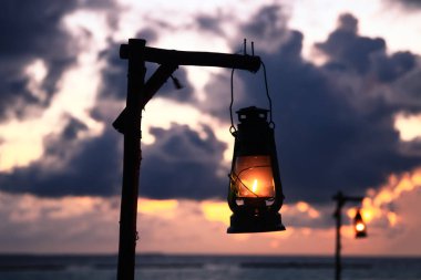 Maldives Island Beach Oil Lamp Lighting and Pacific Ocean at Dusk clipart