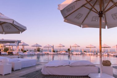 Yüzme havuzu ve güneşlenme yatakları pastel günbatımı ışığı