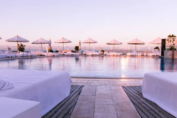 Pastel Sunset Light over Swimming Pool and Sun Beds