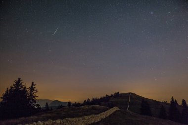 Yıldızlı gece gökyüzü ve kayan yıldız Dağları üzerinde