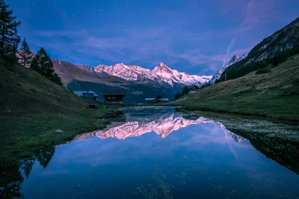 Snowy Mountains and Starry Sky Reflecting in Altitude Lake in Blue Hour