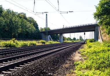 Yaz güneşli bir günde görünür viyadük ve yüksek gerilim hatları ile demiryolu görünümünü izler.