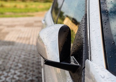 Yağmur damlaları katlanmış yan ayna ile gümüş bir araba.