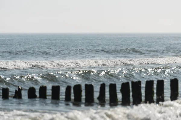 stock image Wooden breakwaters in the baltic sea with rough waves on a summer morning.