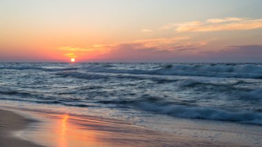 Bir sıcak, yaz akşam kaba dalgalar ile denizde güzel gün batımı.