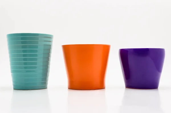 Three flower pots in turquoise, orange and purple colors isolated on a white background with a clipping path.