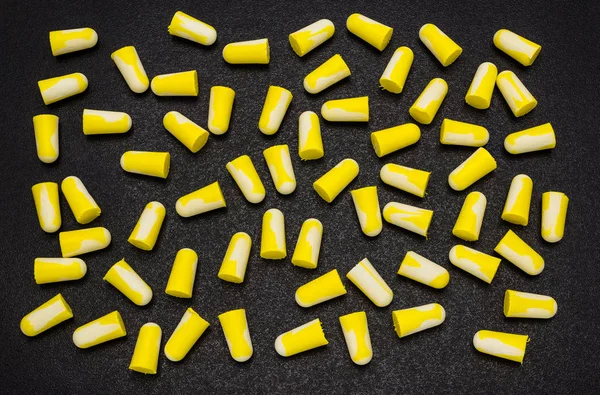 A lot of lying earplugs, for protection against noise in yellow and white, isolated on a black background with a clipping path.