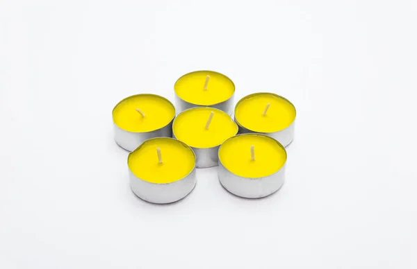 A set of yellow tealight paraffin candle lies on a white background with a clipping path.