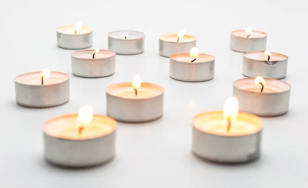 Burning paraffin candles, tealight, lies on a white background.