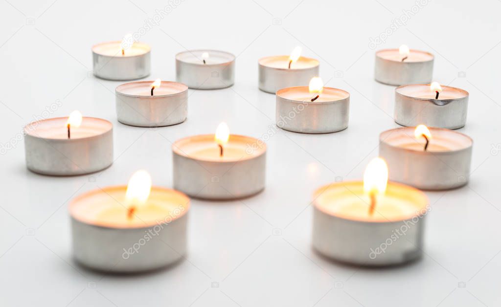 Burning paraffin candles, tealight, lies on a white background.