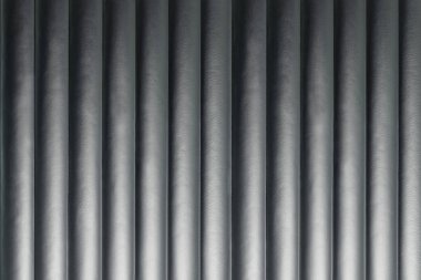 Dikey çizgileri olan soyut gümüş arkaplan, yumuşak bir ışıkla aydınlatılmış.