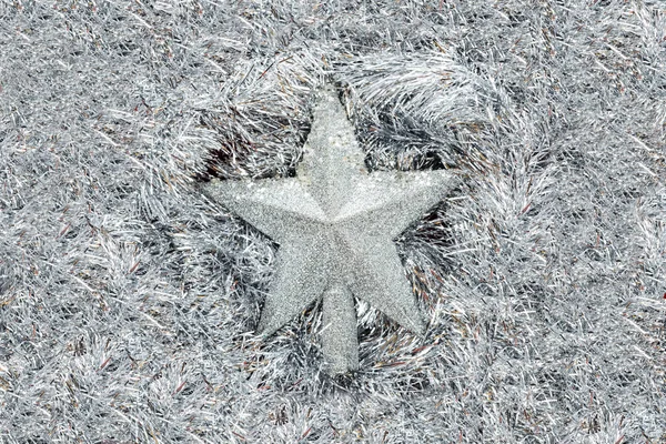 Silver stars lies on a silver tinsel background, christmas decorations.