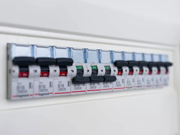 Switches in electrical fuse box. Many black circuit breakers in a row in position ON and three switch in position OFF. Power control panel.