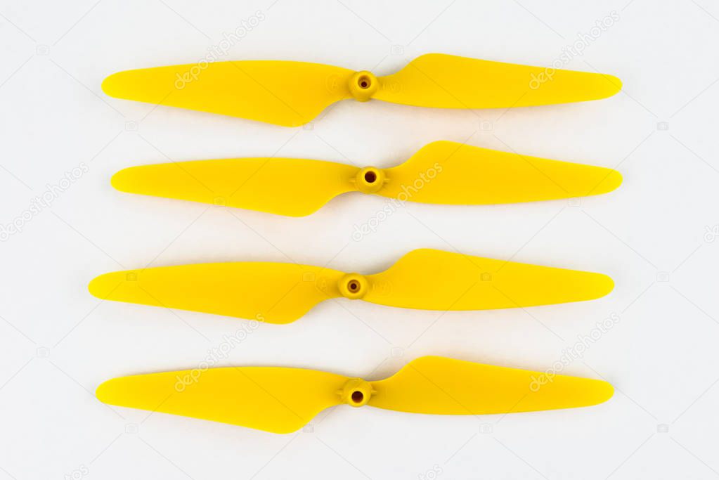 Yellow, plastic propellers for a quadcopter drone, isolated on white background with clipping path. Four pieces arranged in a row.
