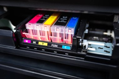 Close-up shot of a CMYK ink cartridges in a color printer.  clipart