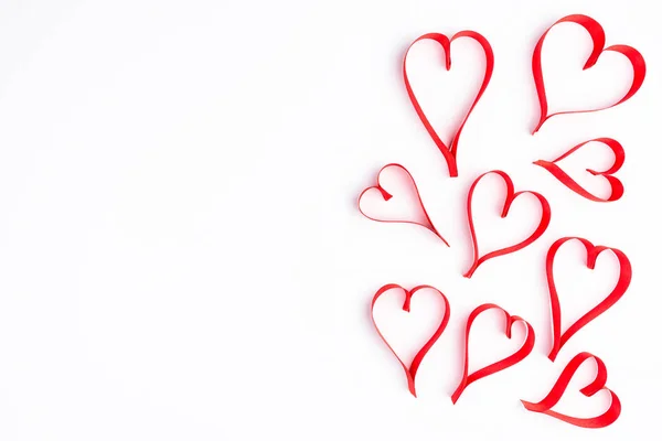 Heart made from red, satin ribbon on white background with clipping path and copy space on the left view from the top. Valentines Day concept.