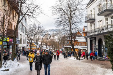Zakopane, Polonya - 22 Şubat 2019. Kişilik bir kalabalık Krupowki cadde boyunca bir kış gününde yürüyor. Krupowki, şehrin ana promenade Zakopane sokaktır. Sokağın Hediyelik eşya dükkanları ile dolu.
