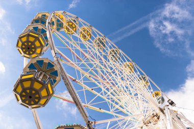 Dönme dolap ile beyaz bulutlar ile güzel bir mavi gökyüzü karşı bir lunapark içinde renkli gondol.