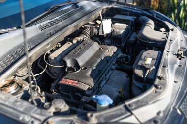 Kirli motor bölmesi içinde kullanılmış araba, motor, kablolar, çizgiler ve rezervuar sıvılar için görünür parçaları.