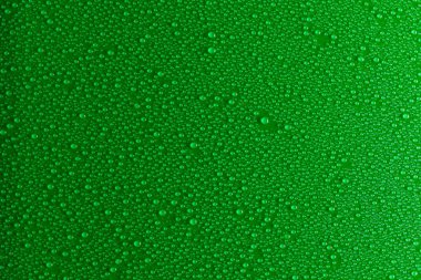 Küçük hassas bir ışıkla aydınlatılmış yeşil, mat bir arka plan üzerinde Su damlacıkları.