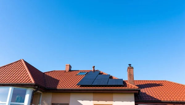 青空の背景に赤の家の屋根に太陽電池パネル — ストック写真