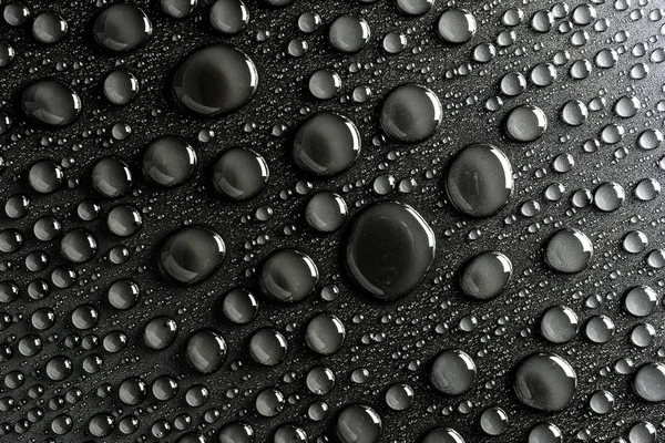 Droplets of water on a black, matte background illuminated with a delicate light.