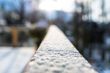 Karla kaplı, Ahşap korkuluk balkon seçici odak ile. Arka plan, bulanık binalar ve ağaçlar.