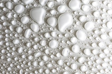 Hassas bir ışıkla aydınlatılmış, mat beyaz arka plan üzerinde Su damlacıkları.