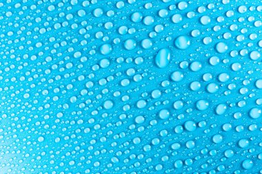 Hassas bir ışıkla aydınlatılmış mavi, mat bir arka plan üzerinde Su damlacıkları.