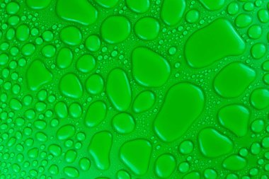 Hassas bir ışıkla aydınlatılmış yeşil, mat bir arka plan üzerinde Su damlacıkları.