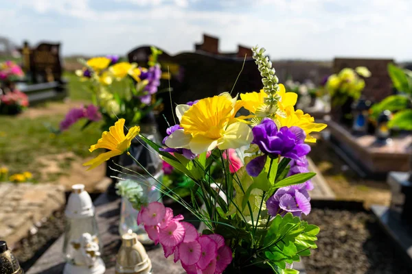 人工花とろうそく足は墓地の墓石の上に横たわっている — ストック写真