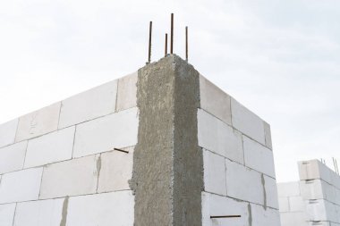 Sonunda nervürlü çubuklar, sütunlardan görülebilen ahşap kalıplar bulunan betonarme sütunlarla beyaz tuğladan yapılmış bir evin duvarları.