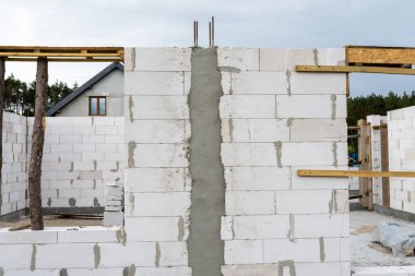 Sonunda nervürlü çubuklar, sütunlardan görülebilen ahşap kalıplar bulunan betonarme sütunlarla beyaz tuğladan yapılmış bir evin duvarları.
