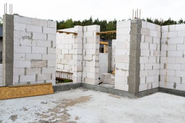 Sonunda nervürlü çubuklar, sütunlardan görülebilen ahşap kalıplar bulunan betonarme sütunlarla beyaz tuğladan yapılmış bir evin duvarları.
