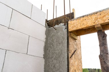Sonunda nervürlü çubuklar, sütunlardan görülebilen ahşap kalıplar bulunan betonarme sütunlarla beyaz tuğladan yapılmış bir evin duvarları.