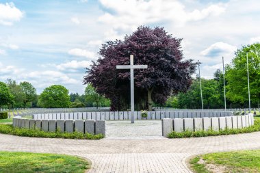 Beyaz bulutlarla mavi bir gökyüzüne karşı mezarlıkta büyük bir beton haç.