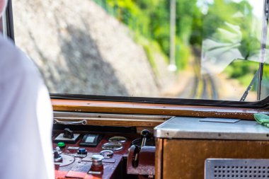 Seyahat eden bir demiryolu treninin penceresinden bir görünüm, tren, gösterge paneli, parça, ağaçlar ve beyaz bulutlarla mavi bir gökyüzü çalıştıran görünür bir motor sürücüsü.