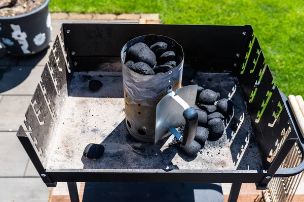 Lighting the home grill with coal, standing on a home garden on the paving stone.